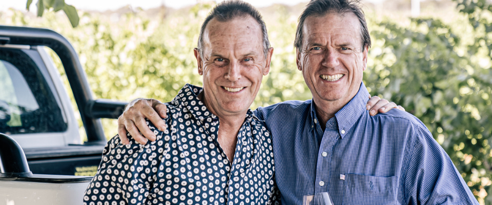 Mal and Bruce standing behind their Ute with their arms around each other 